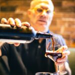man in black crew neck shirt holding clear drinking glass